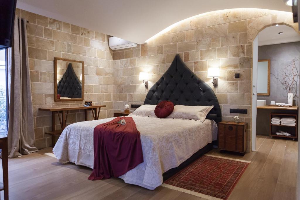 a bedroom with a large bed and a stone wall at Utopia Luxury Suites - Old Town in Rhodes Town