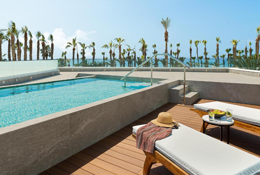 a swimming pool with a table and a hat at GrandResort by Leonardo Hotels in Limassol