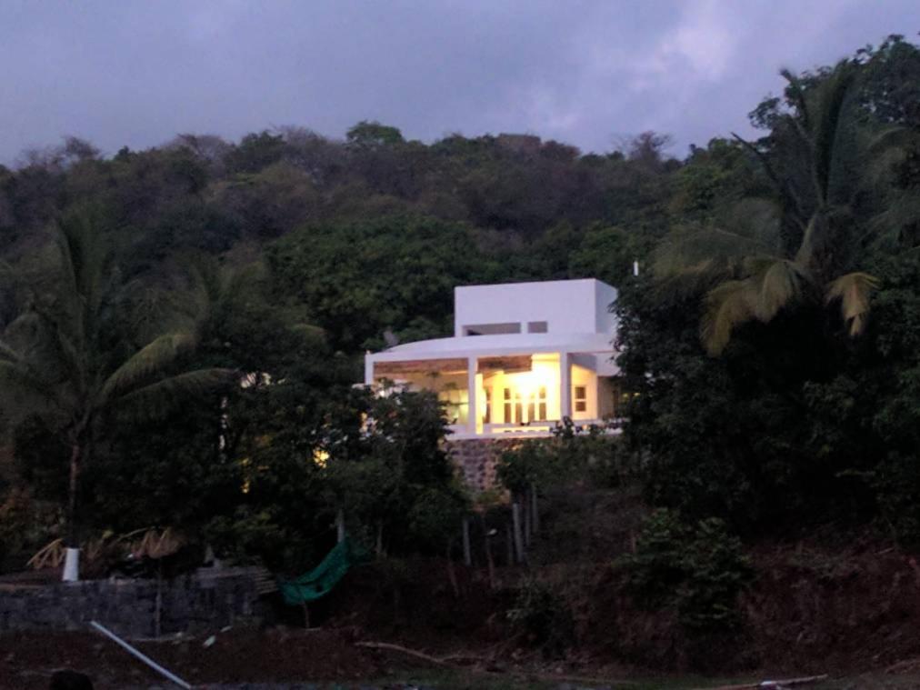 a large white building with lights on in a forest at Ashine villa in Alībāg
