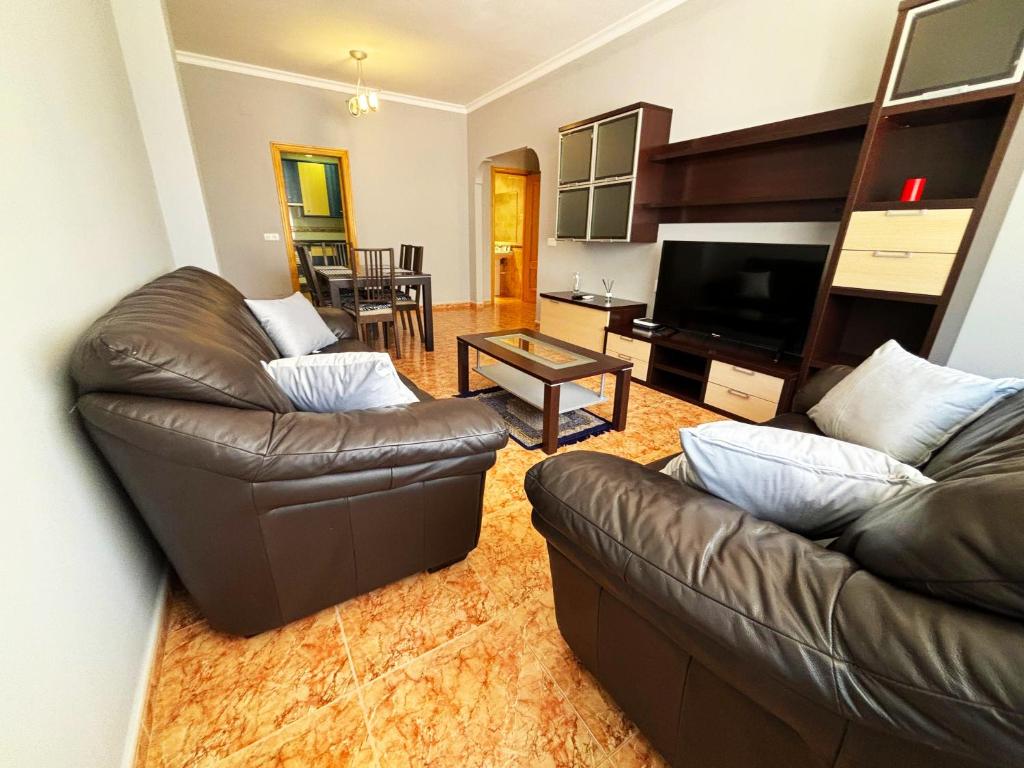 un salon avec deux canapés en cuir et une télévision dans l'établissement BAJBAJ - Apartamento 2 dormitorios a 100 metros de la Playa del Bajondillo, a 300 metros del centro de Torremolinos, à Torremolinos