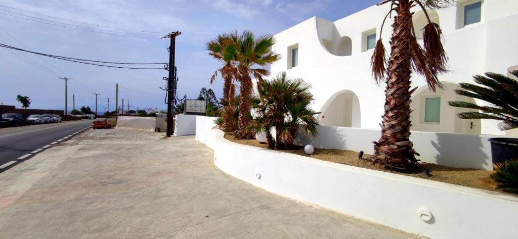 un bâtiment blanc avec des palmiers à côté d'une rue dans l'établissement Mykonian Iros Suites & Villas, à Kalo Livadi