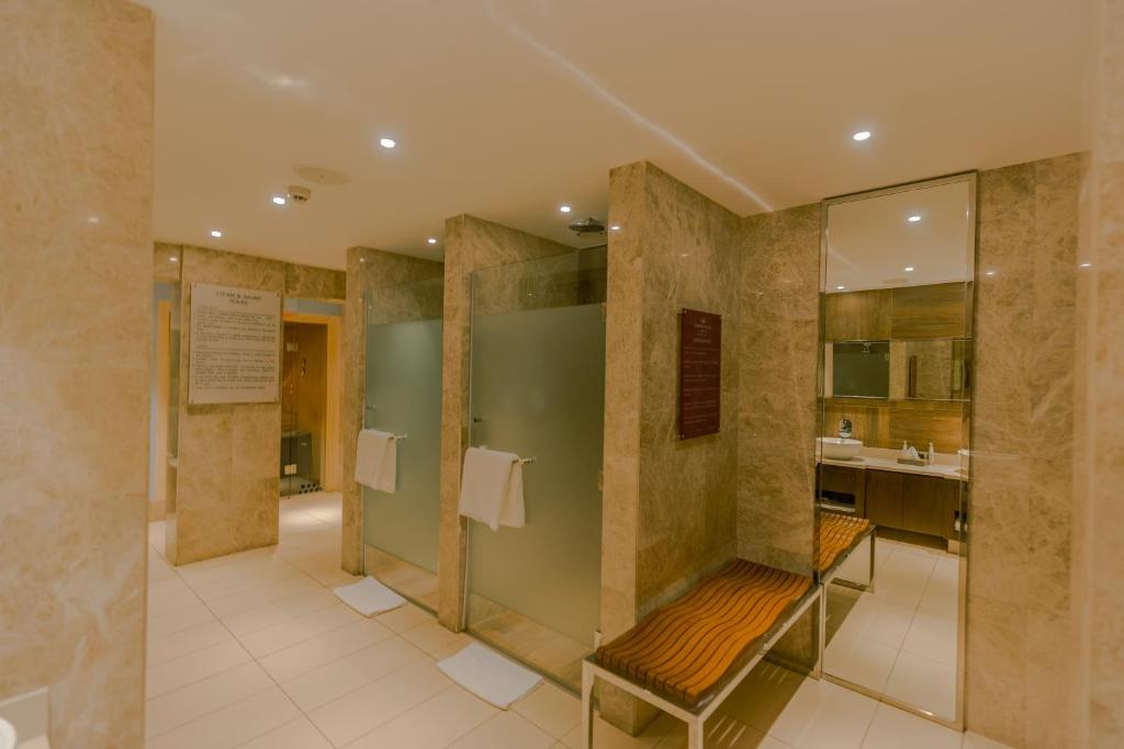 a bathroom with a shower with a bench in it at Crowne Plaza Nairobi Airport by IHG in Nairobi