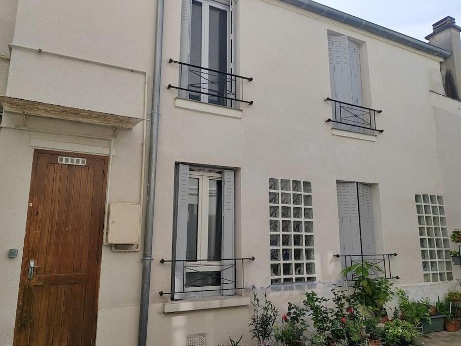 - un bâtiment blanc avec une porte et des fenêtres en bois dans l'établissement Appartement duplex indépendant de 46m2, à Nanterre