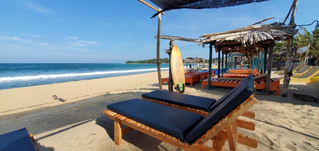 a beach with a chair and a surfboard on the beach at Surf And Stay Arugam Bay in Arugam Bay