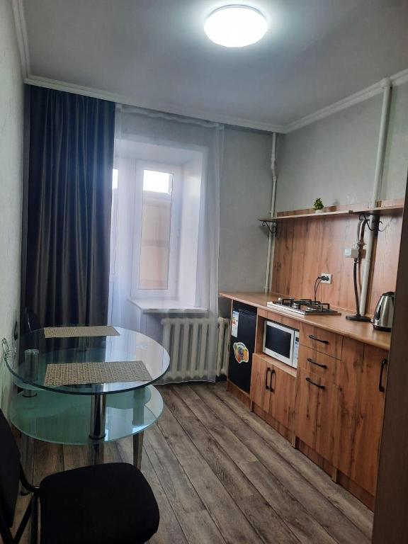 una pequeña cocina con mesa de cristal y fregadero en Сдам 1-комн квартиру в Центре, en Semey