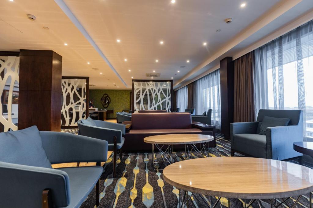 a lobby with couches and tables and windows at Crowne Plaza Nairobi Airport by IHG in Nairobi