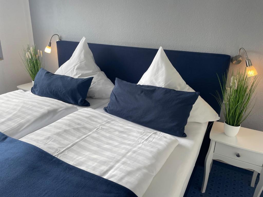 a blue and white bed with blue and white pillows at Hotel KAUP in Paderborn