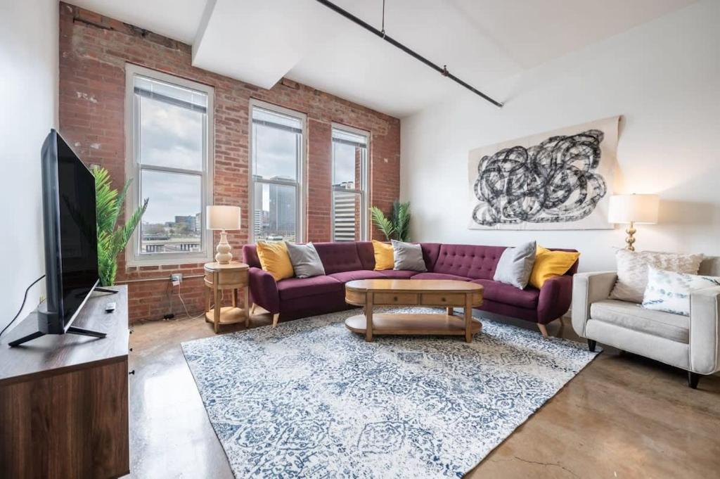 a living room with purple couches and a tv at 3BR 2BA Luxury Historic Loft With Gym by ENVITAE in Kansas City