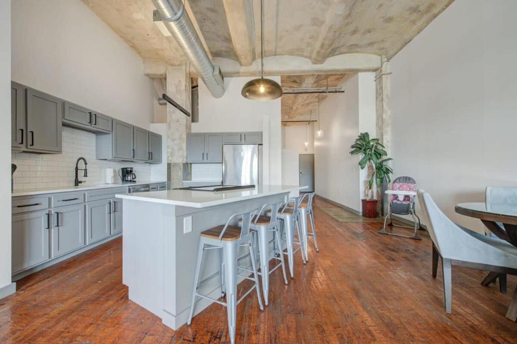 a kitchen with white cabinets and a bar with stools at 2BR 2BA Spacious Historic Loft With Gym by ENVITAE in Kansas City