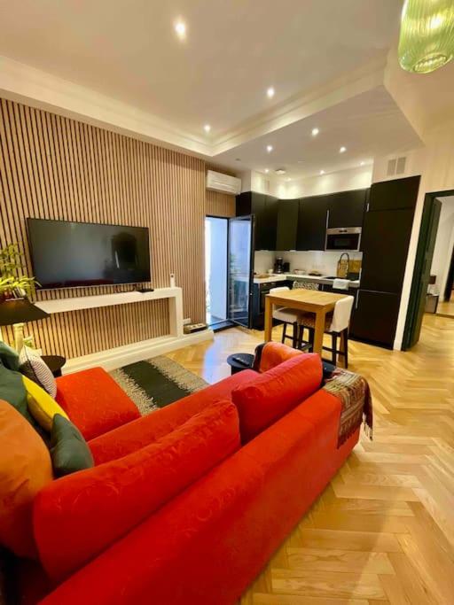 un salon avec un canapé rouge et une cuisine dans l'établissement Superbe T2 cocon en hyper centre-ville d'Ajaccio, à Ajaccio