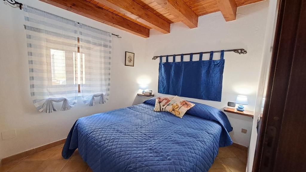 - une chambre avec un lit doté d'une couette bleue et d'une fenêtre dans l'établissement A Nicaredda, à Cefalù