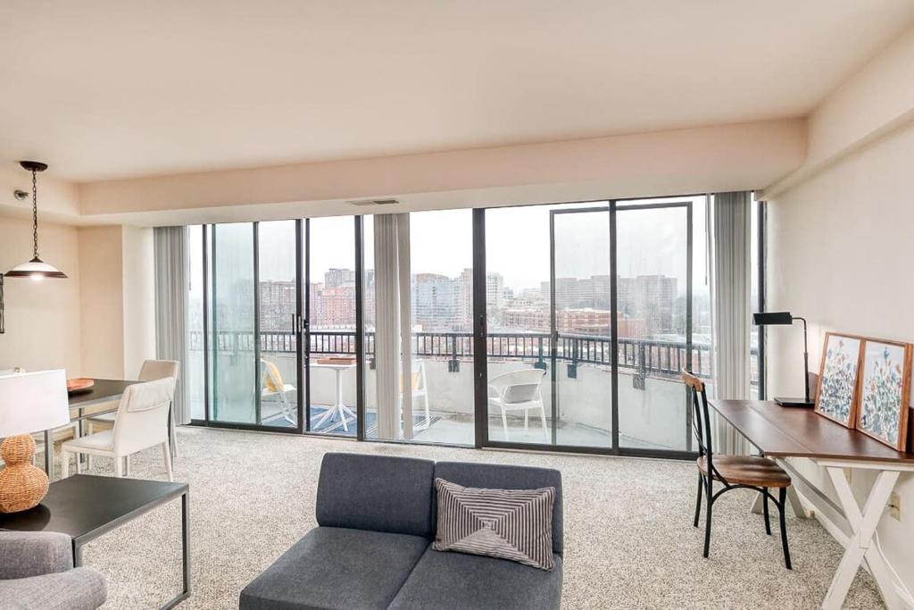 sala de estar con sofá, mesa y algunas ventanas en 2BR Executive Apartment in Prime Location, en Arlington