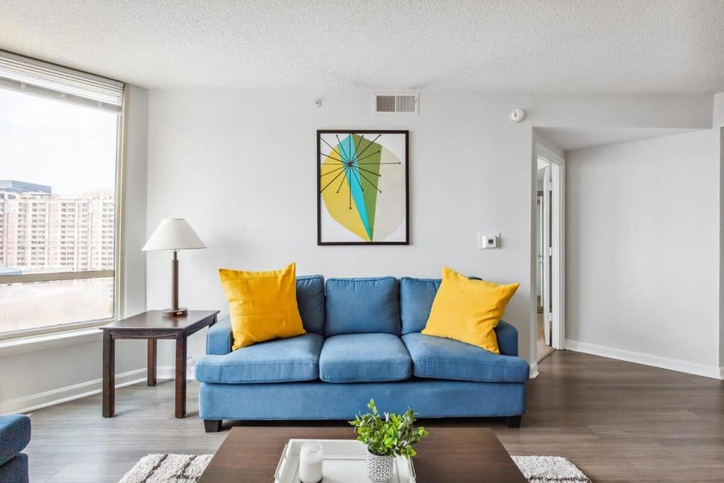 a living room with a blue couch and yellow pillows at 2BR Luxury City Suite With Gym & Pool in Arlington