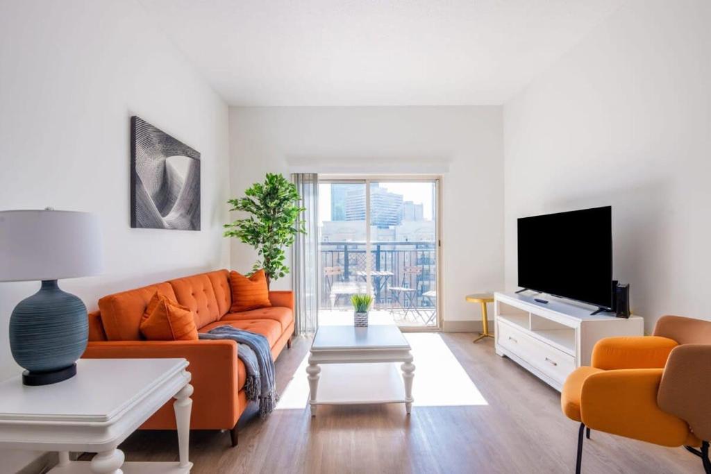 a living room with an orange couch and a tv at 3BR Premium Downtown Apartment with Office & Gym in Charlotte
