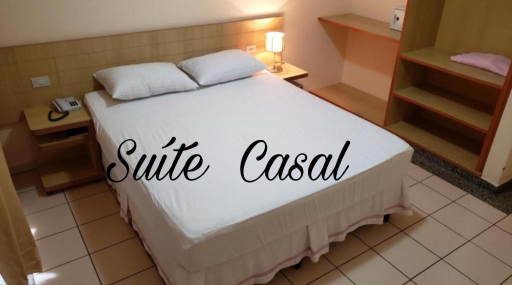 una camera da letto con un letto bianco con un cartello sorrandale sopra di Flat DiRoma. a Rio Quente