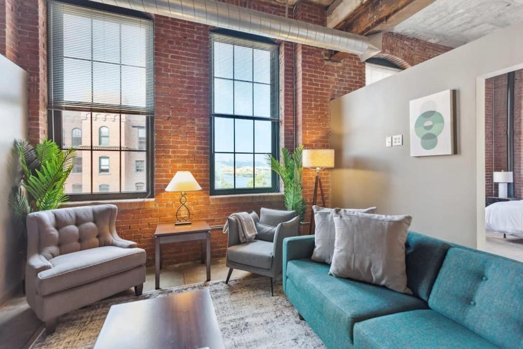 a living room with a blue couch and two chairs at 2BR Spacious Historic Loft With Pool in Pittsburgh