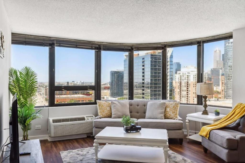 a living room with a couch and large windows at 2BR Modern South Loop Suite With Views & Gym in Chicago