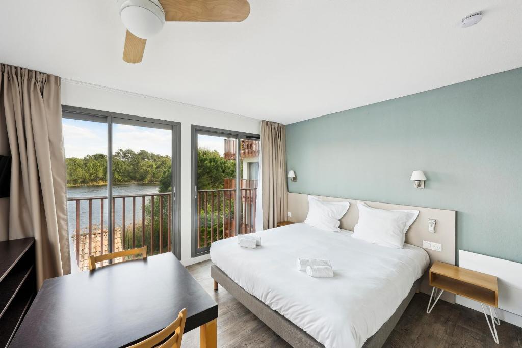 Un dormitorio con una cama y una mesa y un balcón. en All Suites Appart Hôtel - Bassin d&#39;Arcachon - Dune du Pilat, en La Teste-de-Buch