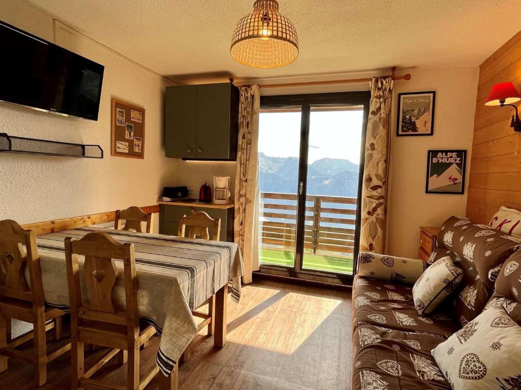 ein Wohnzimmer mit einem Tisch, einem Sofa und einem Fenster in der Unterkunft Appartement Huez, 2 pièces, 5 personnes - FR-1-405-346 in Huez