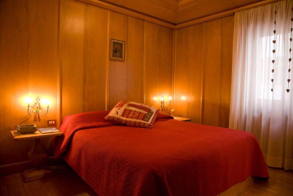 a bedroom with a red bed and a window at Casa Viola in Cortina dʼAmpezzo