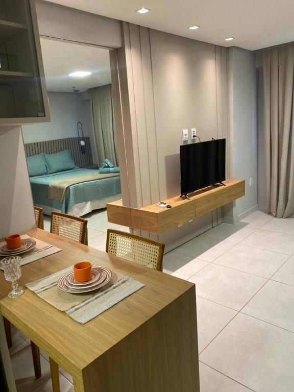 ein Wohnzimmer mit einem Esstisch und einem TV in der Unterkunft Inova Flats premium no Condominio Cosmopolitan in Palmas