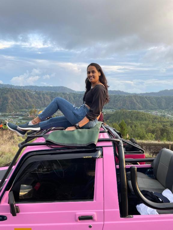 a woman sitting on the top of a pink truck at jeep tour sunrise batur in Kintamani