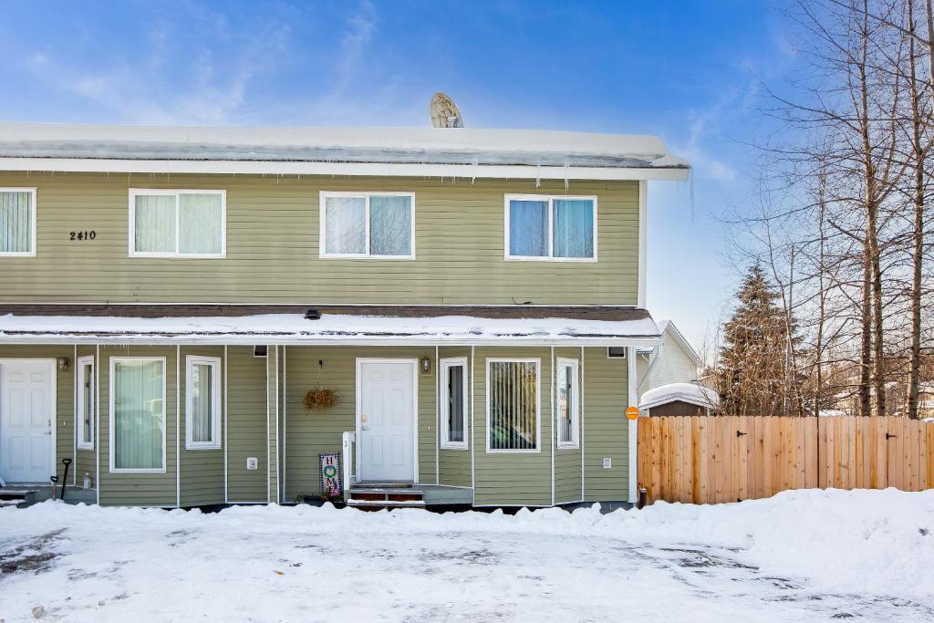 uma casa verde com neve em frente em Alaska Hog House: Cozy & Spacious home Anchorage em Anchorage