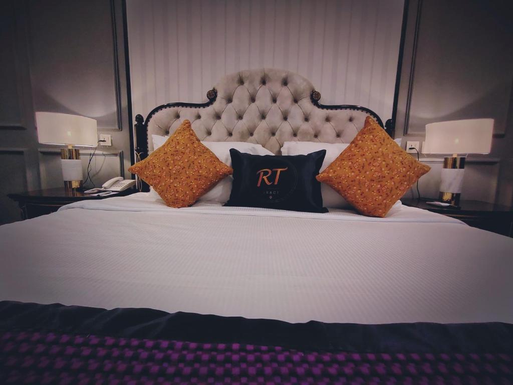 una cama con almohadas con el rtk en ella en RT Grace Royal Taj Hotel Sukkur, en Kalar Goth