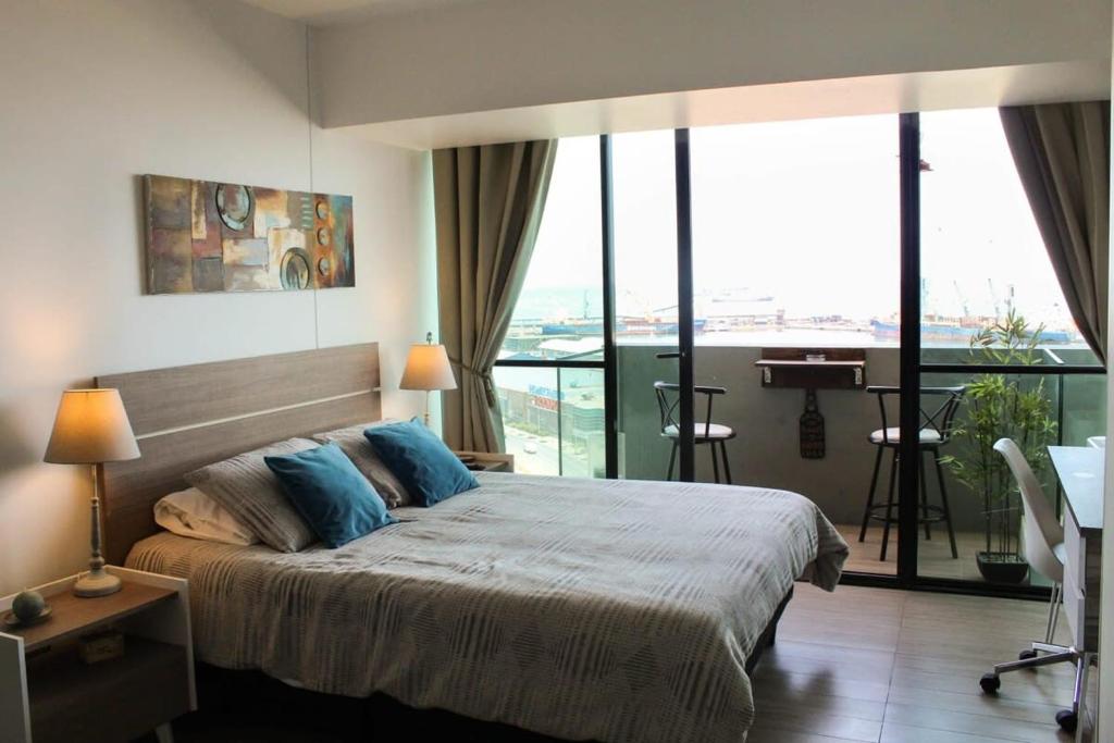 a bedroom with a large bed and a balcony at Depto Estudio con Vista al Mar y Estacionamiento Servicio HOM 1016 in Antofagasta