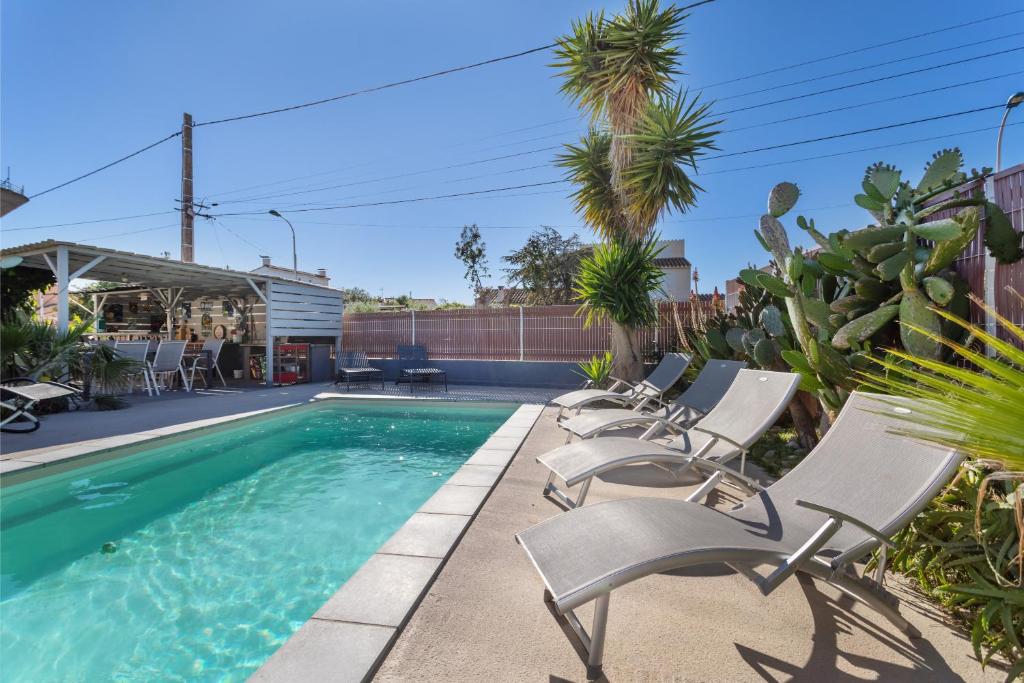 - une piscine avec des chaises longues à côté dans l'établissement Notre cocon mer et montagne, à Villelongue-de-la-Salanque