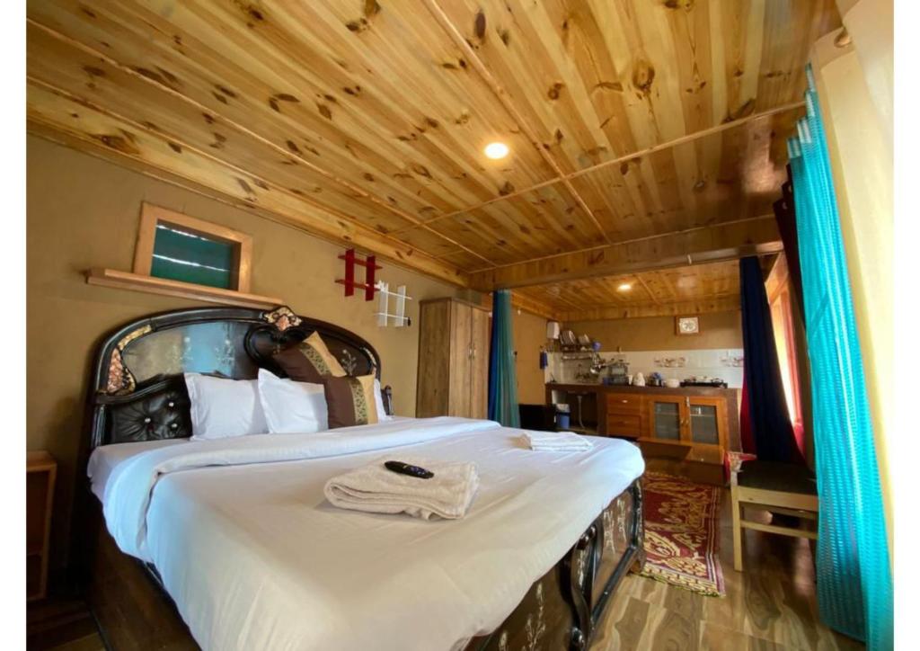 een slaapkamer met een bed en een houten plafond bij Zingo 1BHK Mudhouse in Manāli