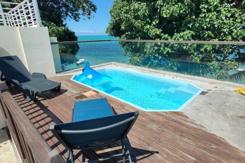 einen Pool auf einer Terrasse mit Stühlen und einem Tisch in der Unterkunft Villa la Perle, piscine privée, vue sur le lagon in Mahébourg