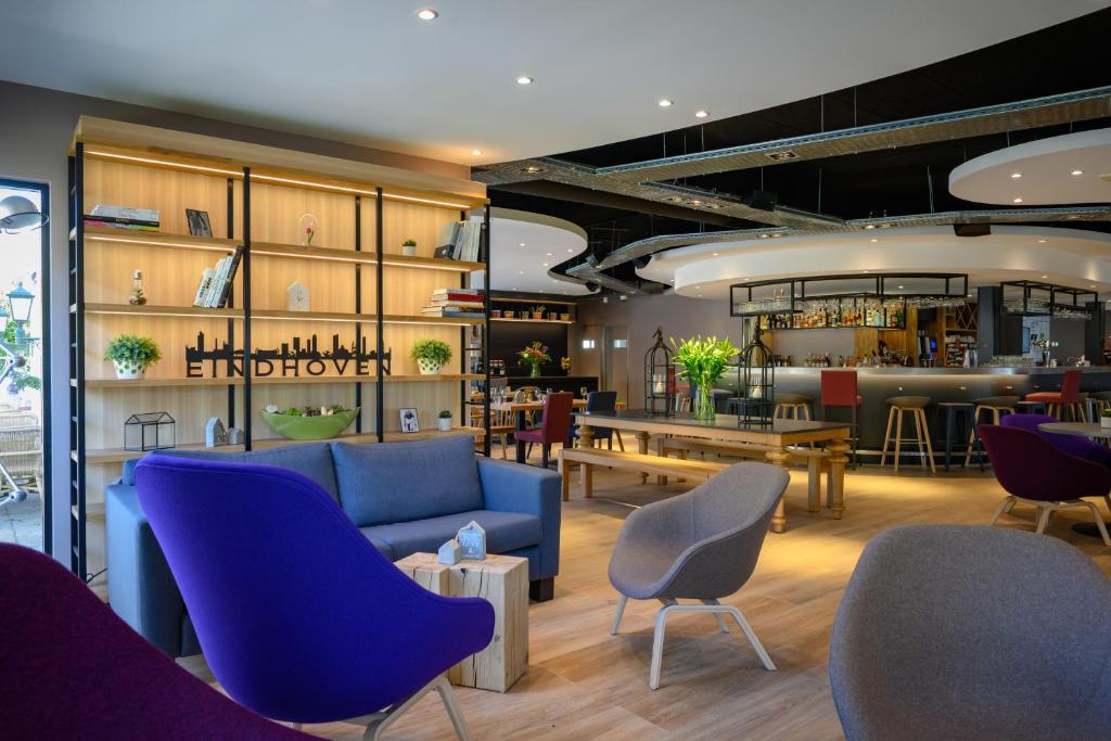 a lobby with a blue couch and chairs and a bar at Campanile Hotel & Restaurant Eindhoven in Eindhoven