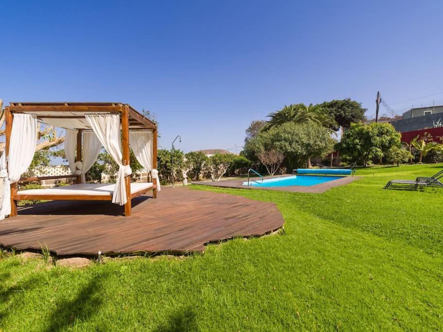 a wooden deck with a bed and a gazebo at Villa with Pool and sea views in Banana Plantation in Arucas