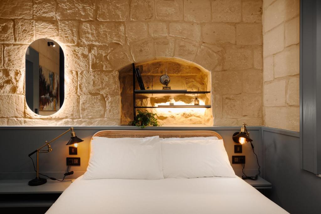 uma cama num quarto com uma parede de pedra em Felipe x Casa Norte em Birgu