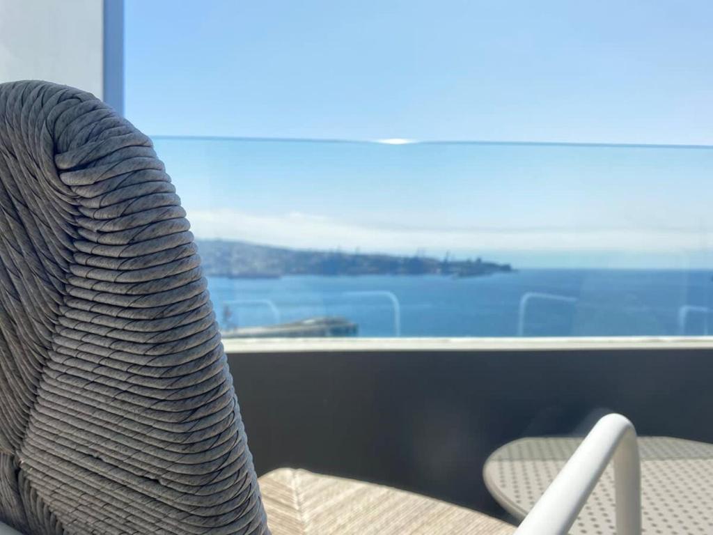 a rattan chair sitting in front of a window at HOM I EnValparaiso, Loft Ubicado en MiradorBarón Parking 1613 in Valparaíso