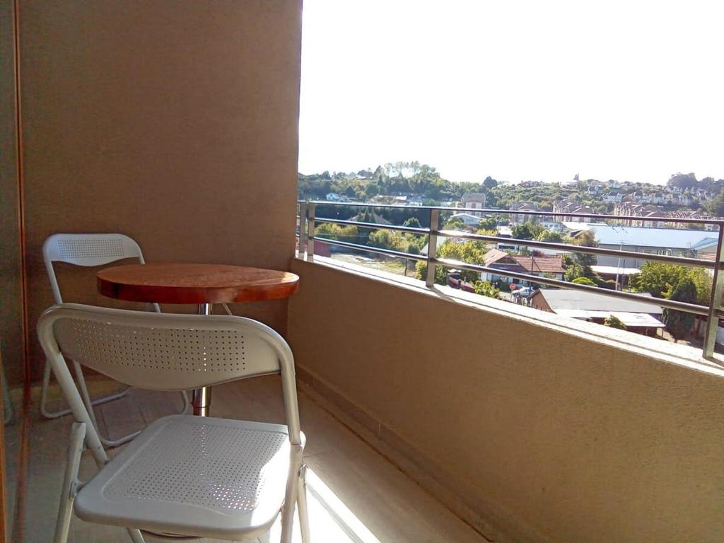 a balcony with a table and two chairs and a window at Mejor Ubicación de Puerto Varas con Estacionamiento Servicio HOM in Puerto Varas