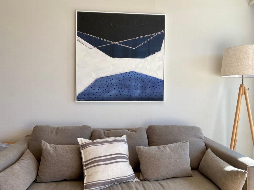 una sala de estar con sofá y una pintura en la pared en Depto 2D2B Frente a la Costanera Piscina Temperada Servicio HOM 0401, en Puerto Varas