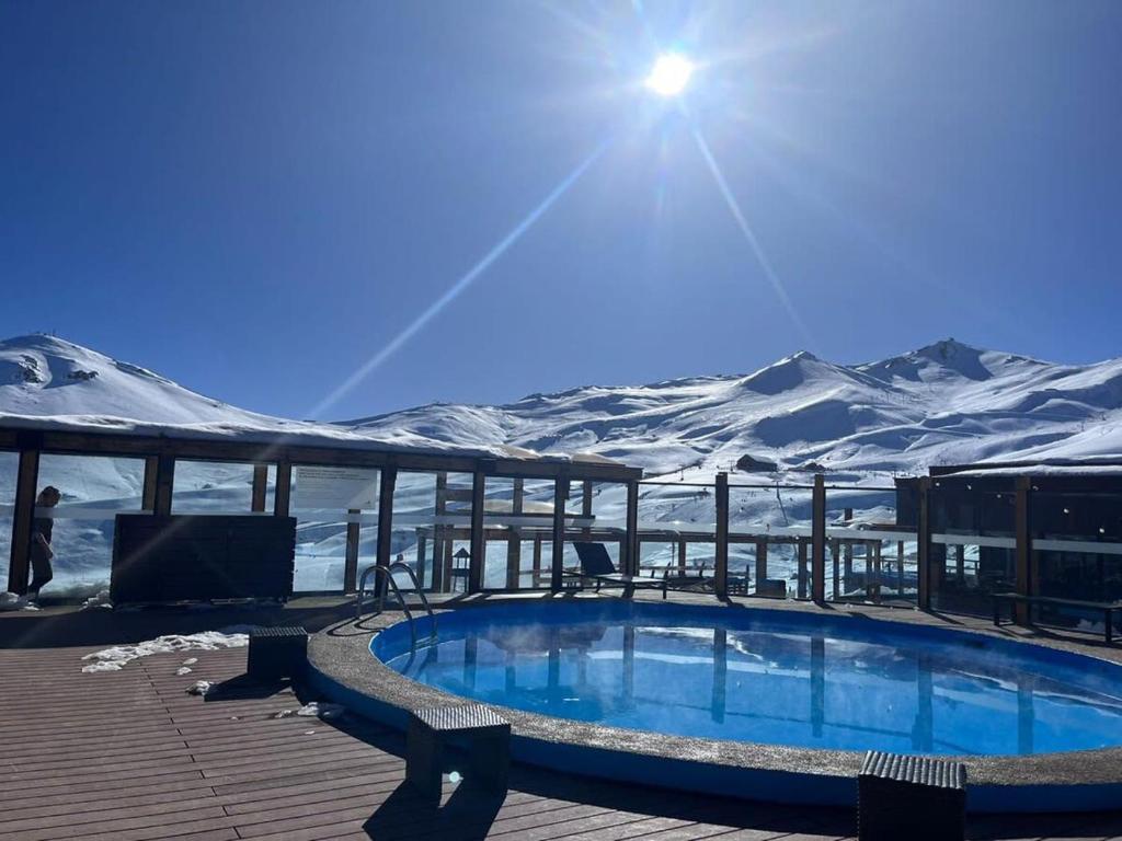 a swimming pool on a deck with snow covered mountains at Edif Mirador del Inca Espectacular Loft En Valle Nevado 10PAX Piscina in Lo Barnechea