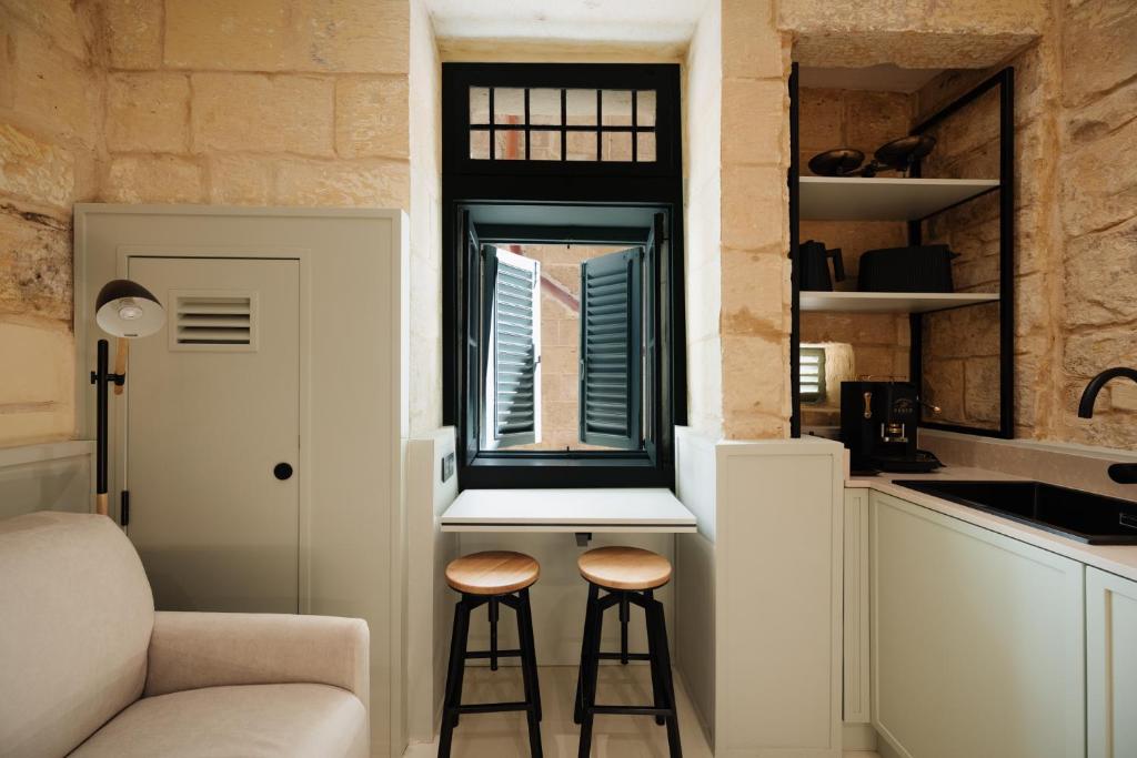 una pequeña cocina con 2 taburetes en una pequeña habitación en Lorenzo x Casa Norte en Birgu