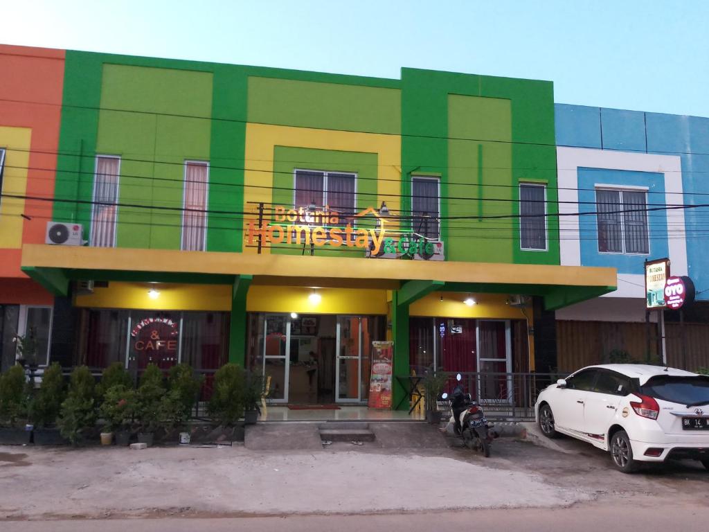 a brightly colored building with a car parked in front at BOTANIA HOMESTAY BATAM in Nongsa
