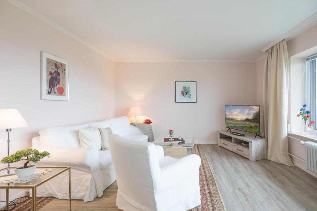 a white living room with a white couch and a tv at Utsicht in Halebüll