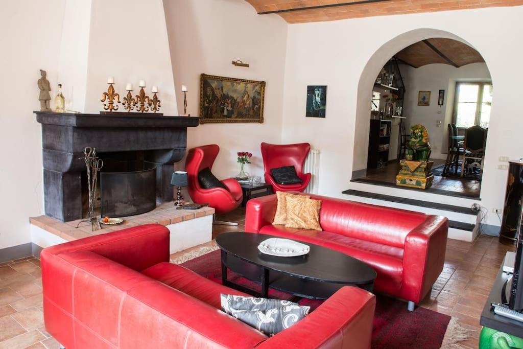 een woonkamer met rode meubels en een open haard bij Oasi nel cuore del Chianti in San Sano