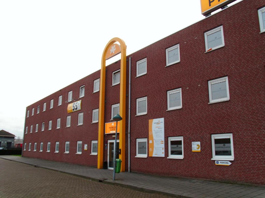 un gran edificio de ladrillo rojo con un poste amarillo en Premiere Classe Hotel Breda, en Breda