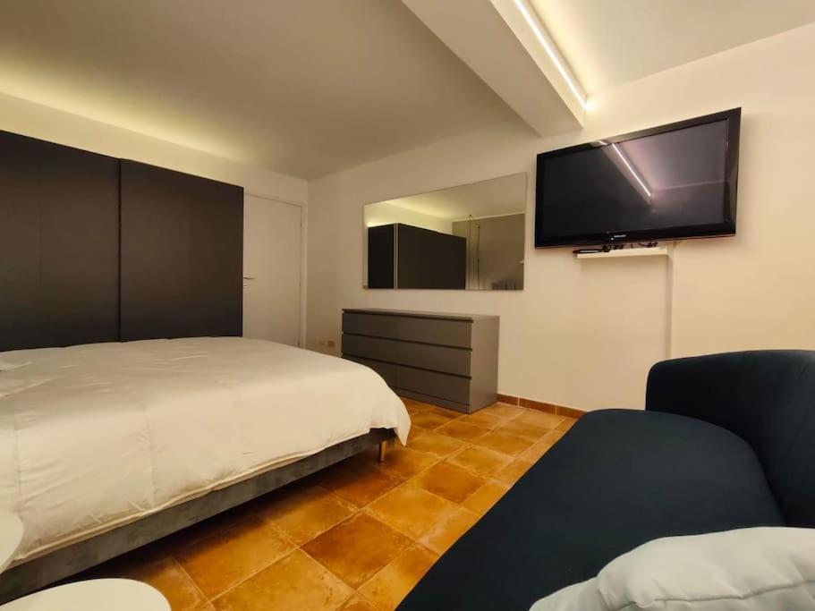 1 dormitorio con 1 cama y TV de pantalla plana en Poseidon - scogliera della baia del Vetrano, en Augusta