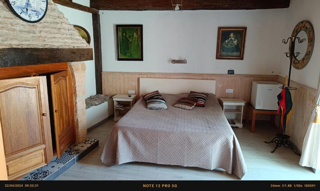 レ・ゼイジー・ド・タヤックにあるChambres d'Hôtes & Gites Pougetのベッドルーム1室(ベッド1台、壁掛け時計付)