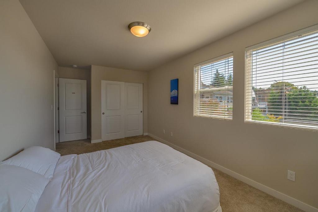 a bedroom with a white bed and two windows at Seattle Urban Village -Private Room- Vashon - Roof Top View Deck in Seattle