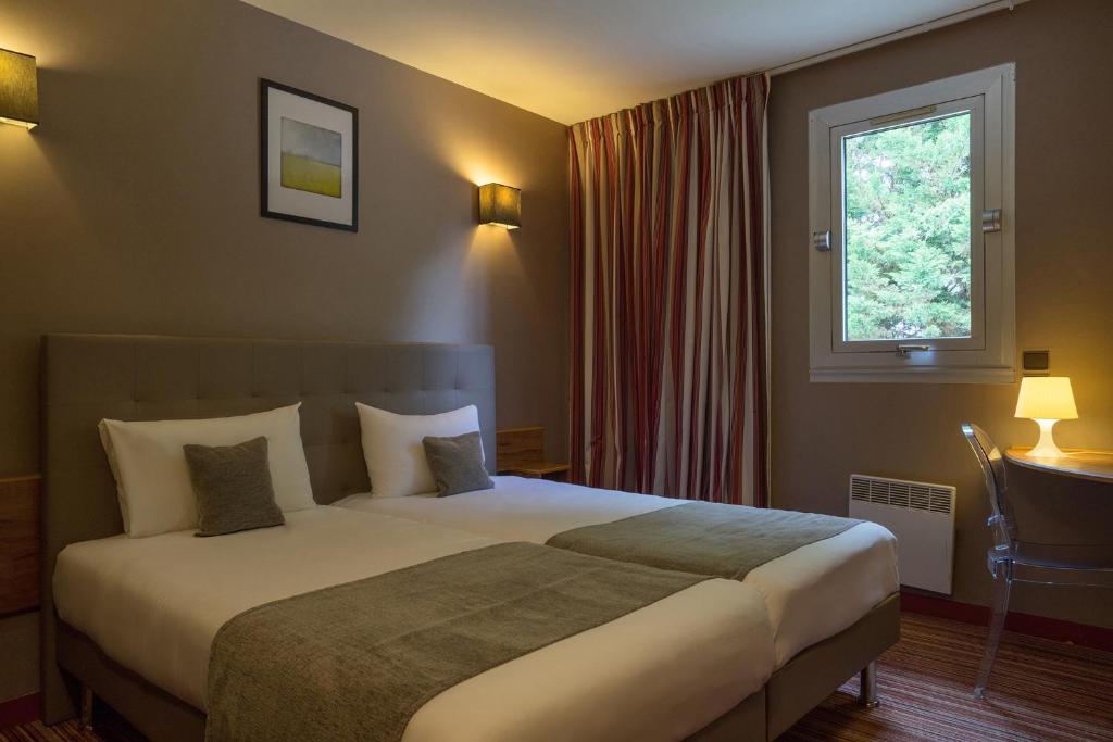 a hotel room with a bed and a window at The Originals City, Hôtel Solana, Niort Est MendesFrance in Niort