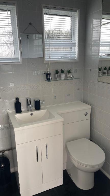 a white bathroom with a toilet and a sink at 25. Valencia in Selsey