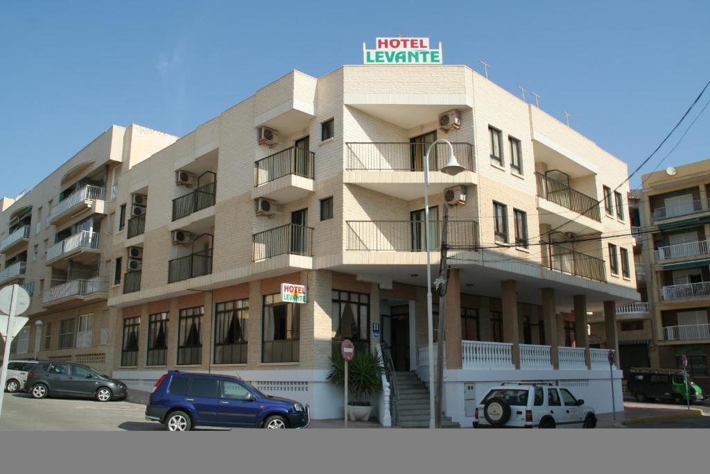 un edificio con coches estacionados frente a él en Hotel Levante, en Guardamar del Segura